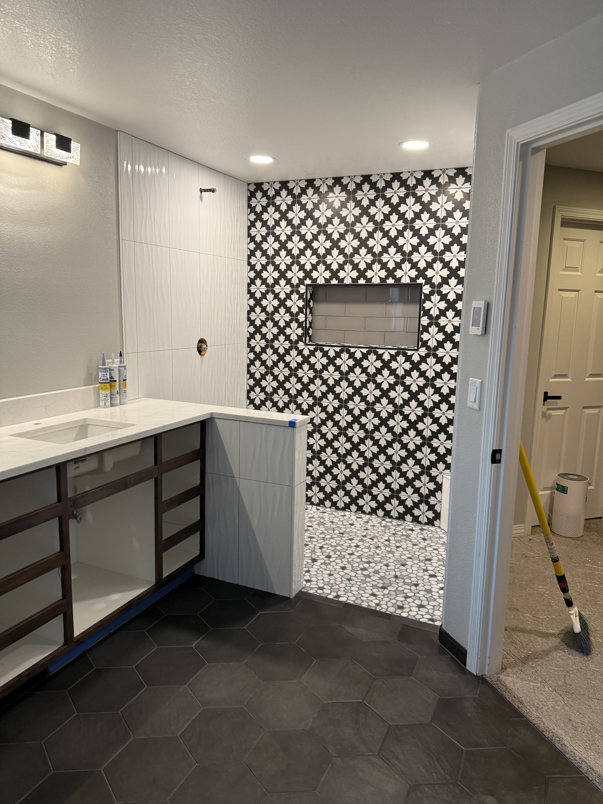 Primary bathroom with black and white patterned tile shower and hexagon floor tile by Castor's Flooring